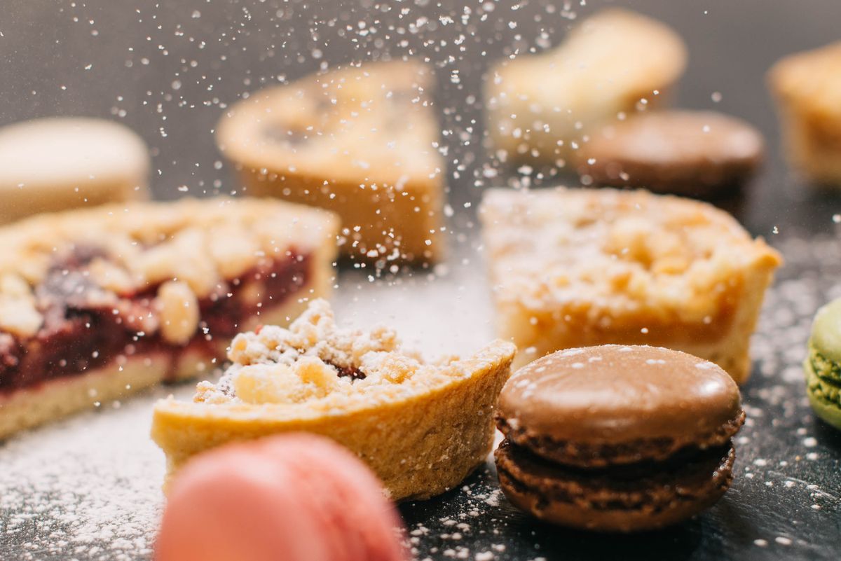 Close-up of delicious pastries and macarons dusted with powdered sugar.