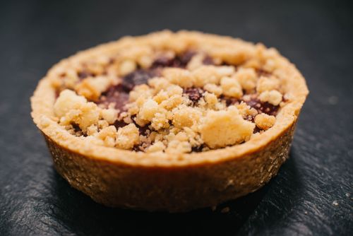 Free Delicious berry tart with crumble on top, showcased with a soft focus, perfect for dessert photography. Stock Photo