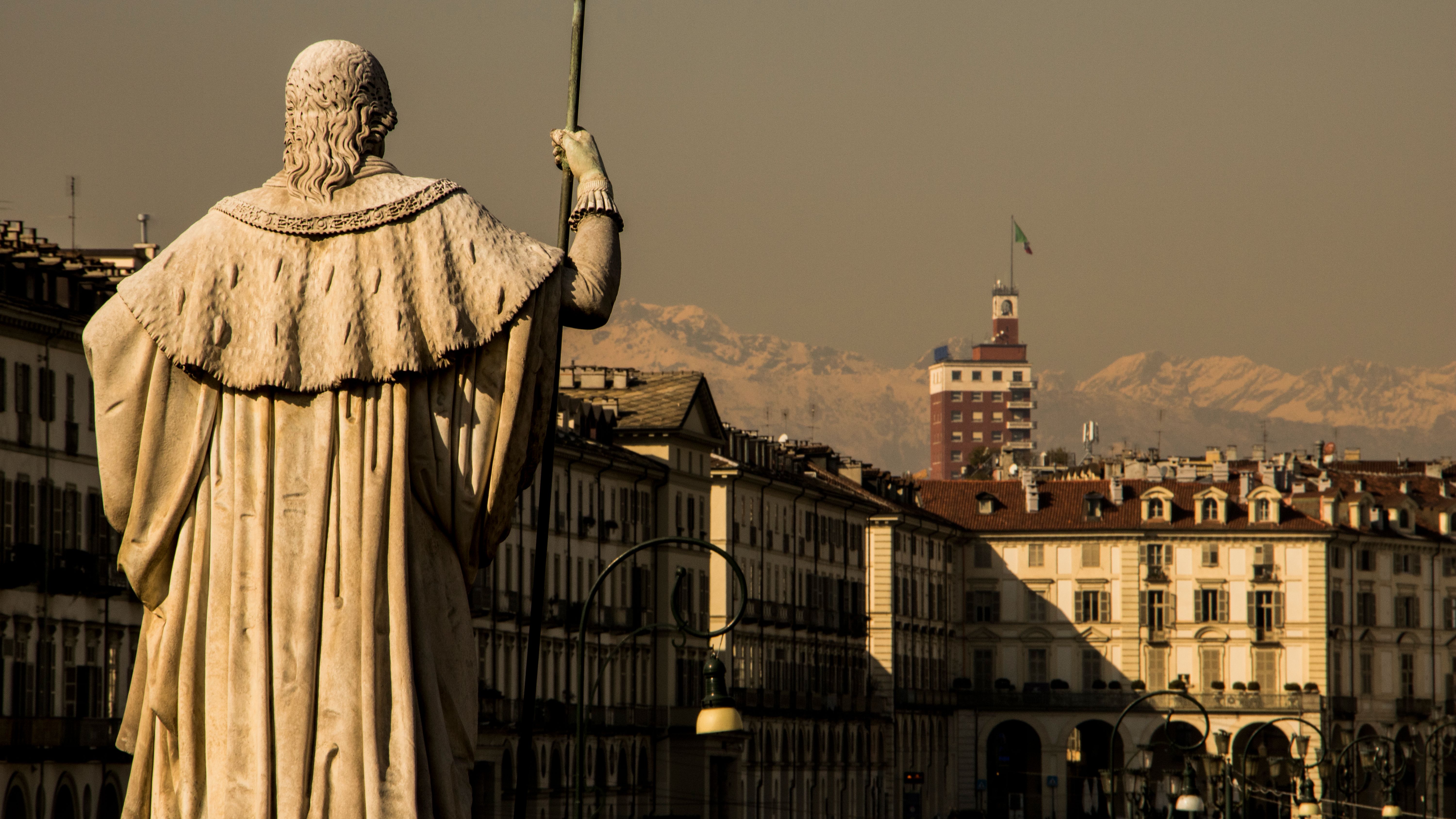 Turin's baroque rooftops and arcades with the snow-covered Alps rising on the horizon behind them