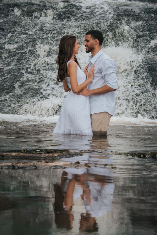 Free A couple embraces by a waterfall, creating a romantic and serene atmosphere. Stock Photo