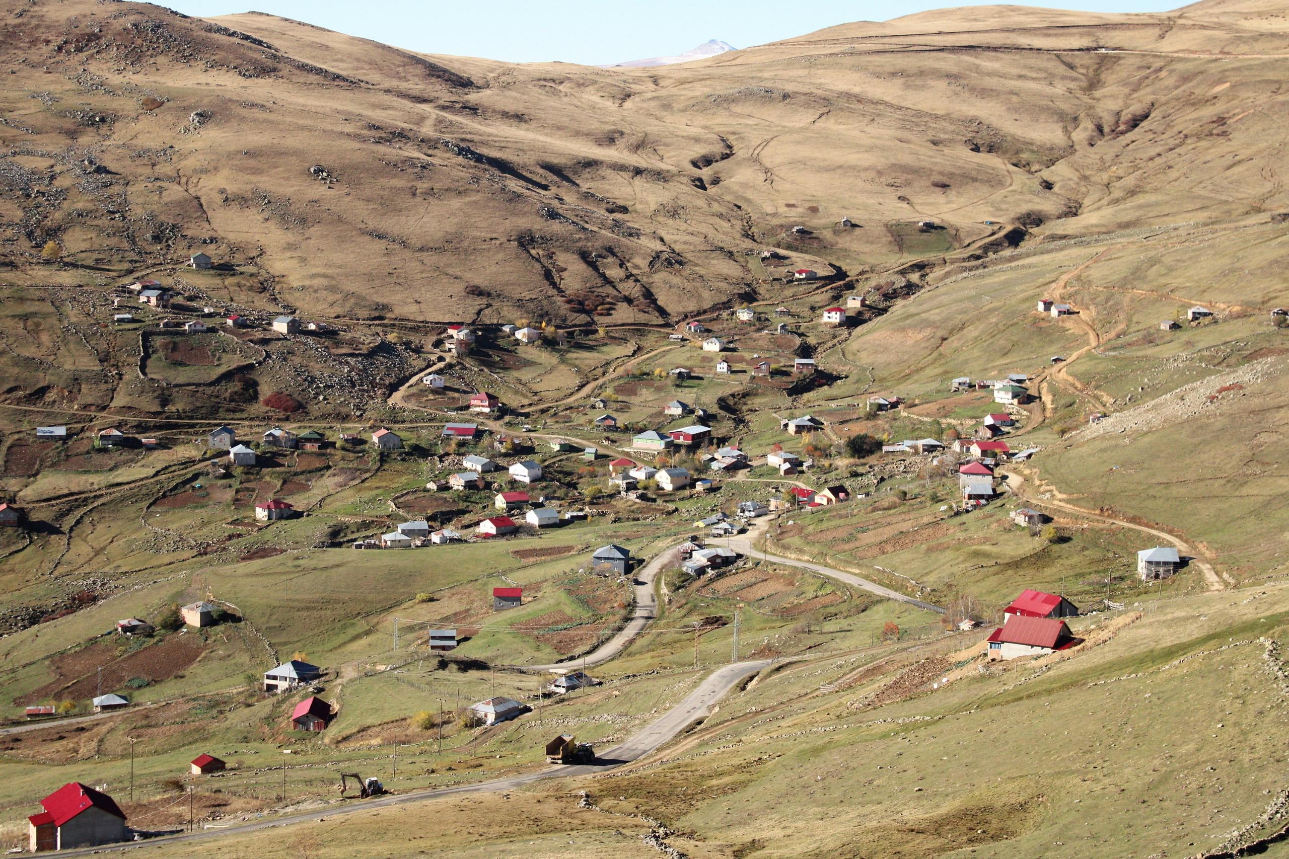 Aerial view of a rural mountain village with scattered homes and winding roads.