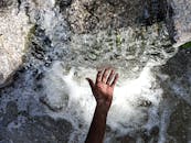 伸手触摸岩石上的小瀑布，捕捉流动的水与自然之美