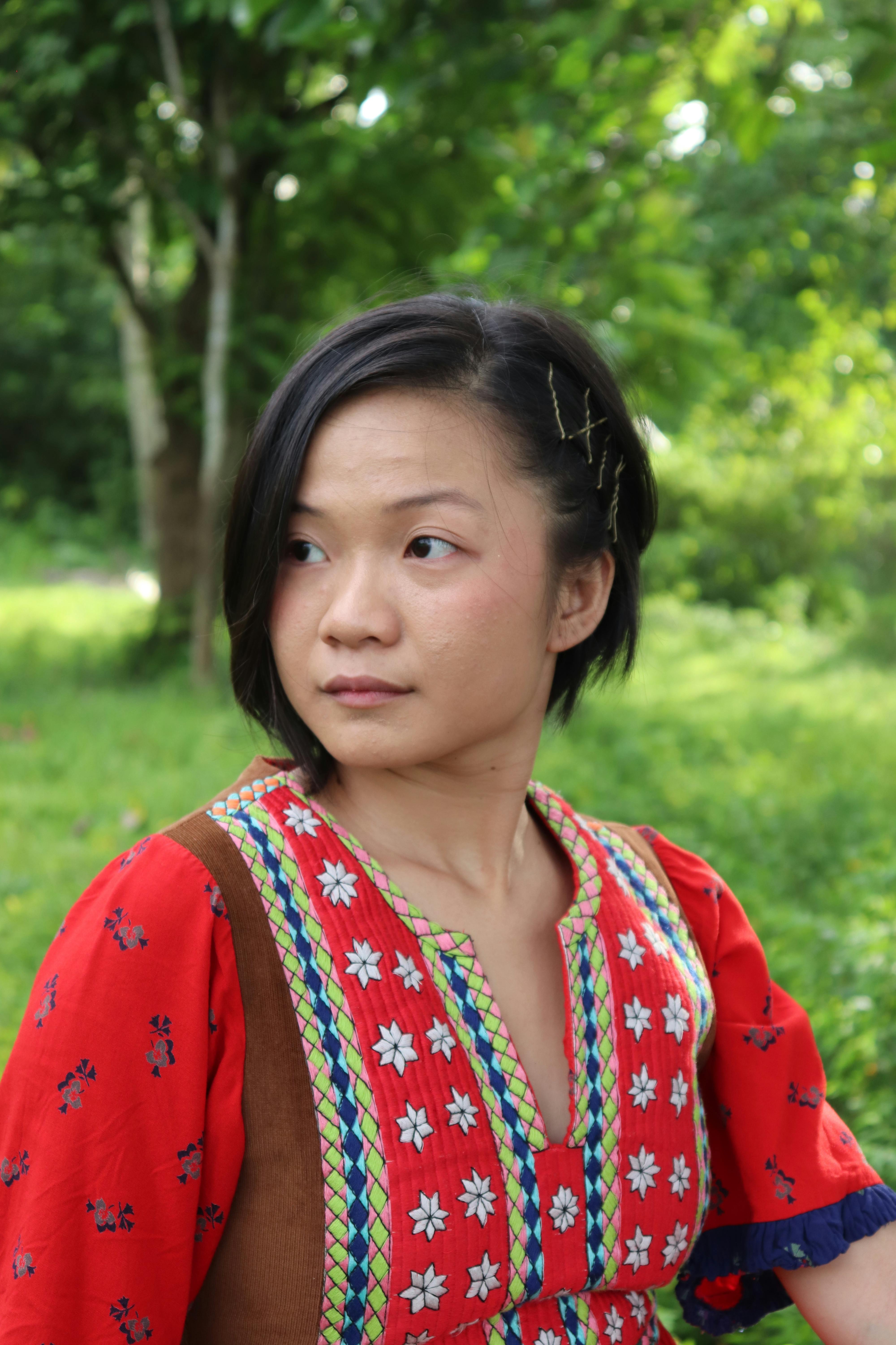 A portrait of a Filipino woman in a traditional dress in a lush outdoor setting.