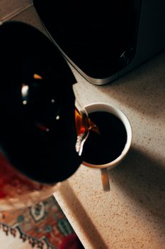 Close-up of freshly brewed coffee being poured into a white mug on a kitchen counter.