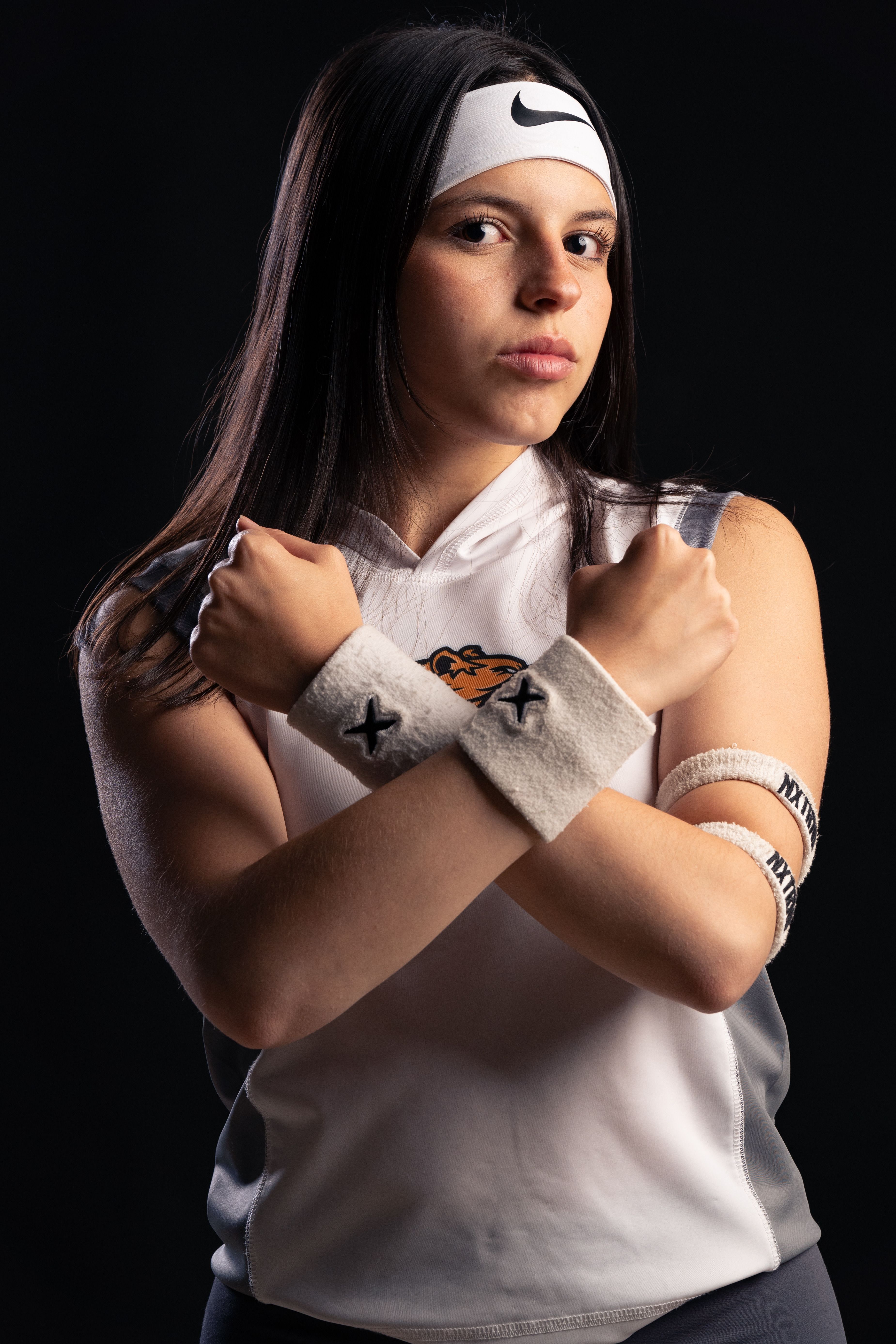 Portrait of a young female athlete crossing arms in sporty outfit, exuding confidence.