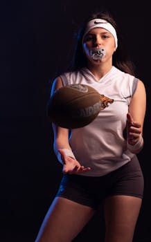 Young female athlete catching a football wearing sports gear and a mouthguard.