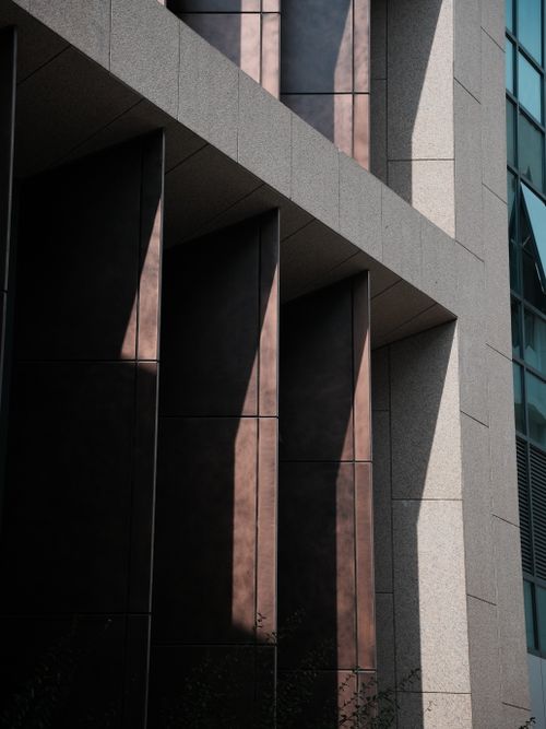 Free Contemporary building facade with dramatic shadows casting geometric patterns. Stock Photo