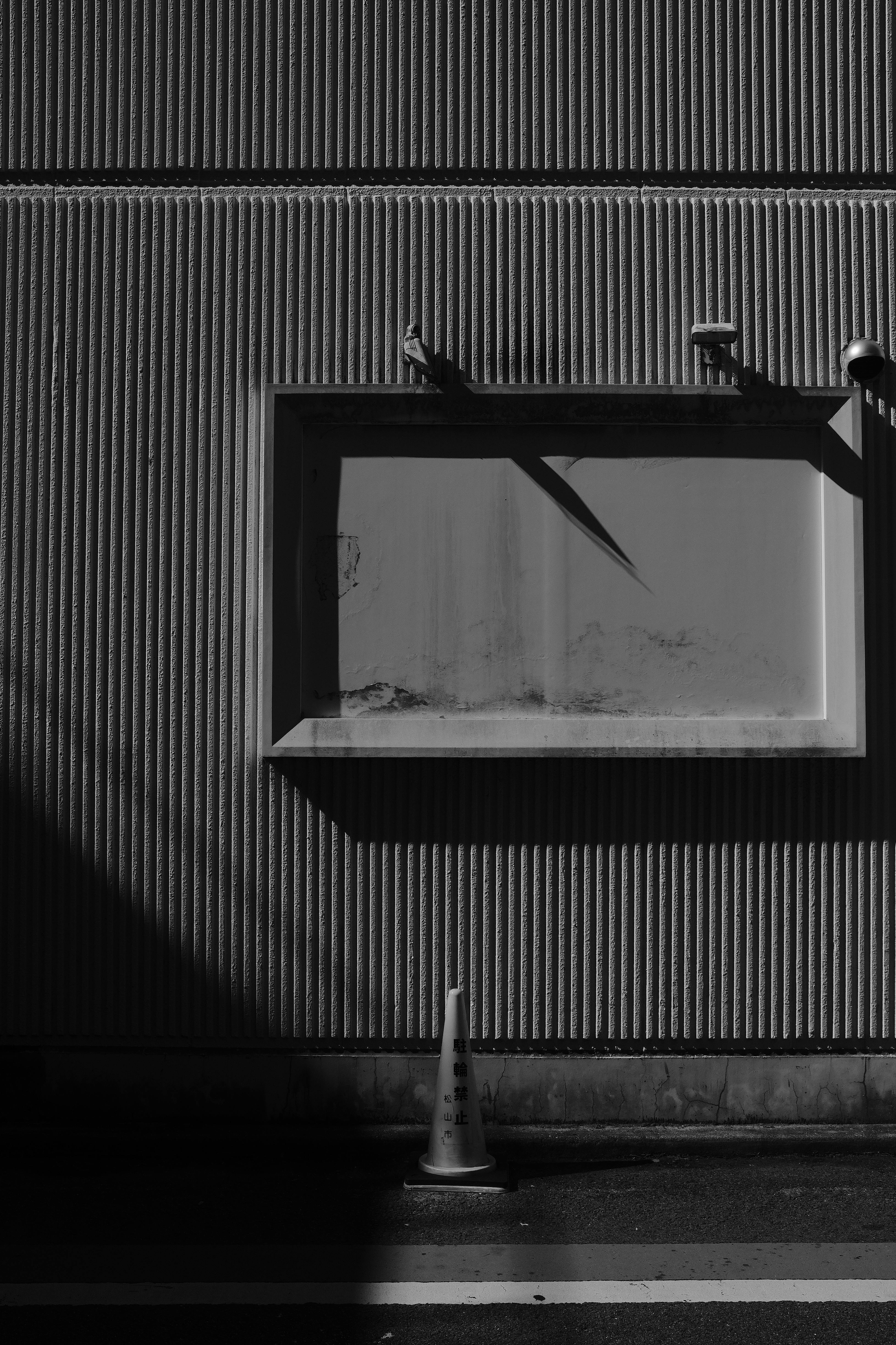 Δωρεάν Ασπρόμαυρη αστική σκηνή με παράθυρο και κώνο κυκλοφορίας που δημιουργούν αντιθετικές σκιές. Φωτογραφία από στοκ φωτογραφιών