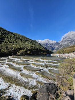 Scenic view of Blue Moon Valley's terraced waterfalls in Yunnan, China under clear blue skies.