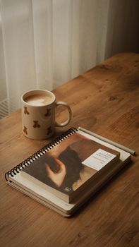A warm, stylish scene with a book and coffee on a wooden table, perfect for relaxation.