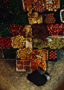 Aerial view of a colorful fruit market stand with a person browsing produce.