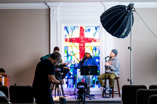Photographer captures live music session indoors with vibrant stained glass backdrop and professional lighting.