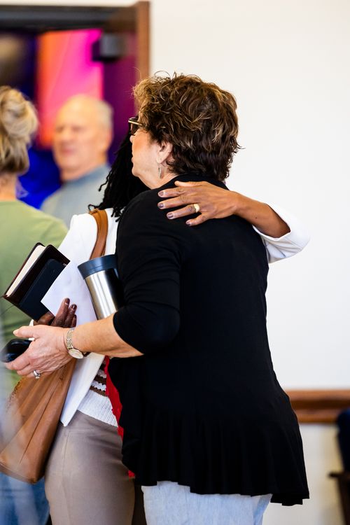 Free Adults embracing in a warm greeting at a social event indoors. Stock Photo