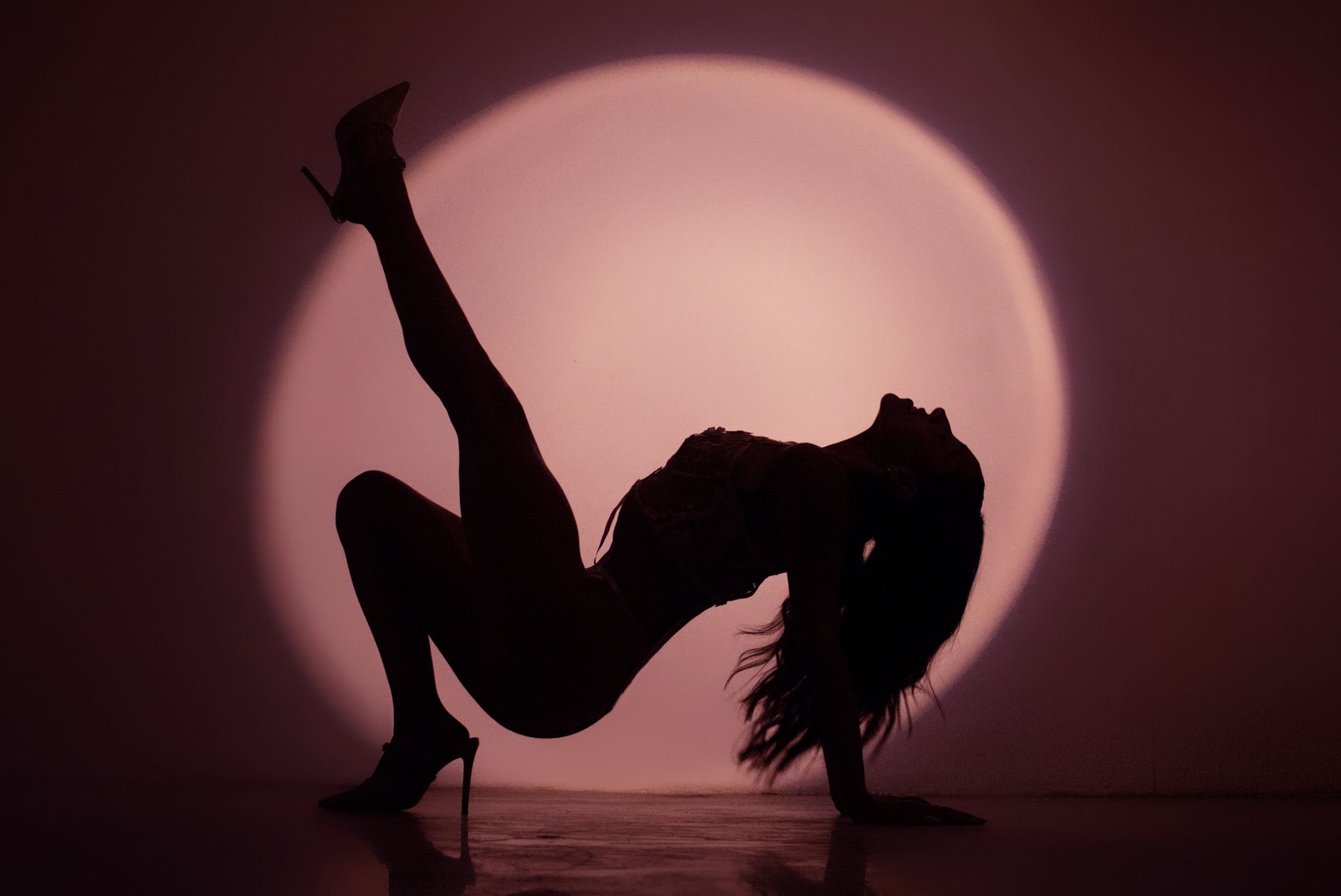 Artistic silhouette of a dancer posing against dramatic studio lighting.