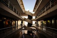 Interior view of a mall with a central spiral staircase and upper walkway levels.