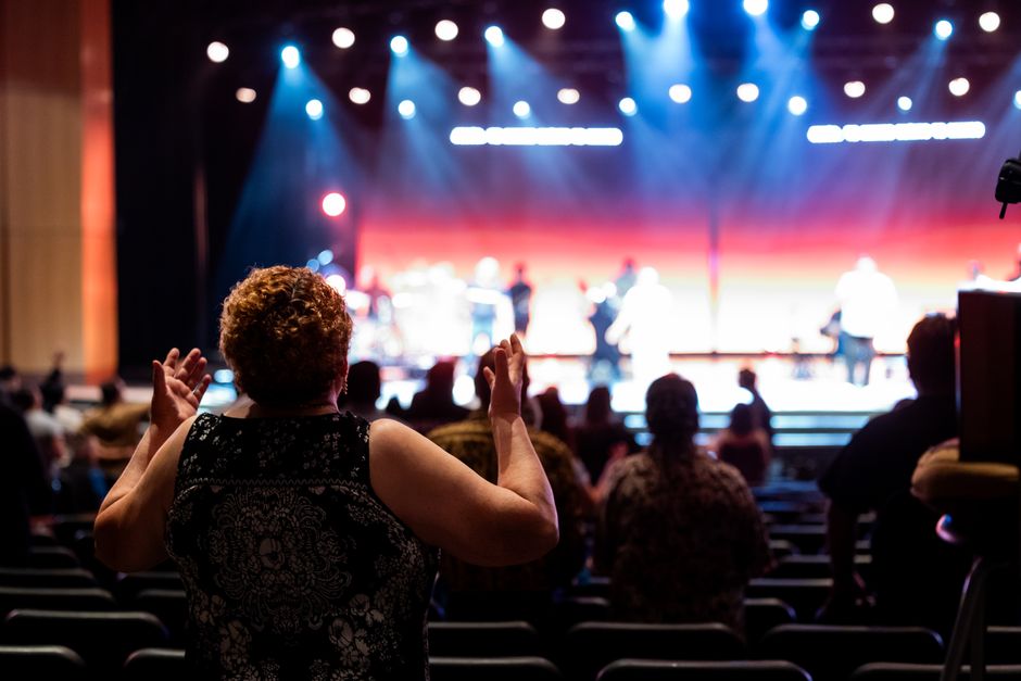 A lively concert setting with an engaged audience clapping, under vibrant stage lights.