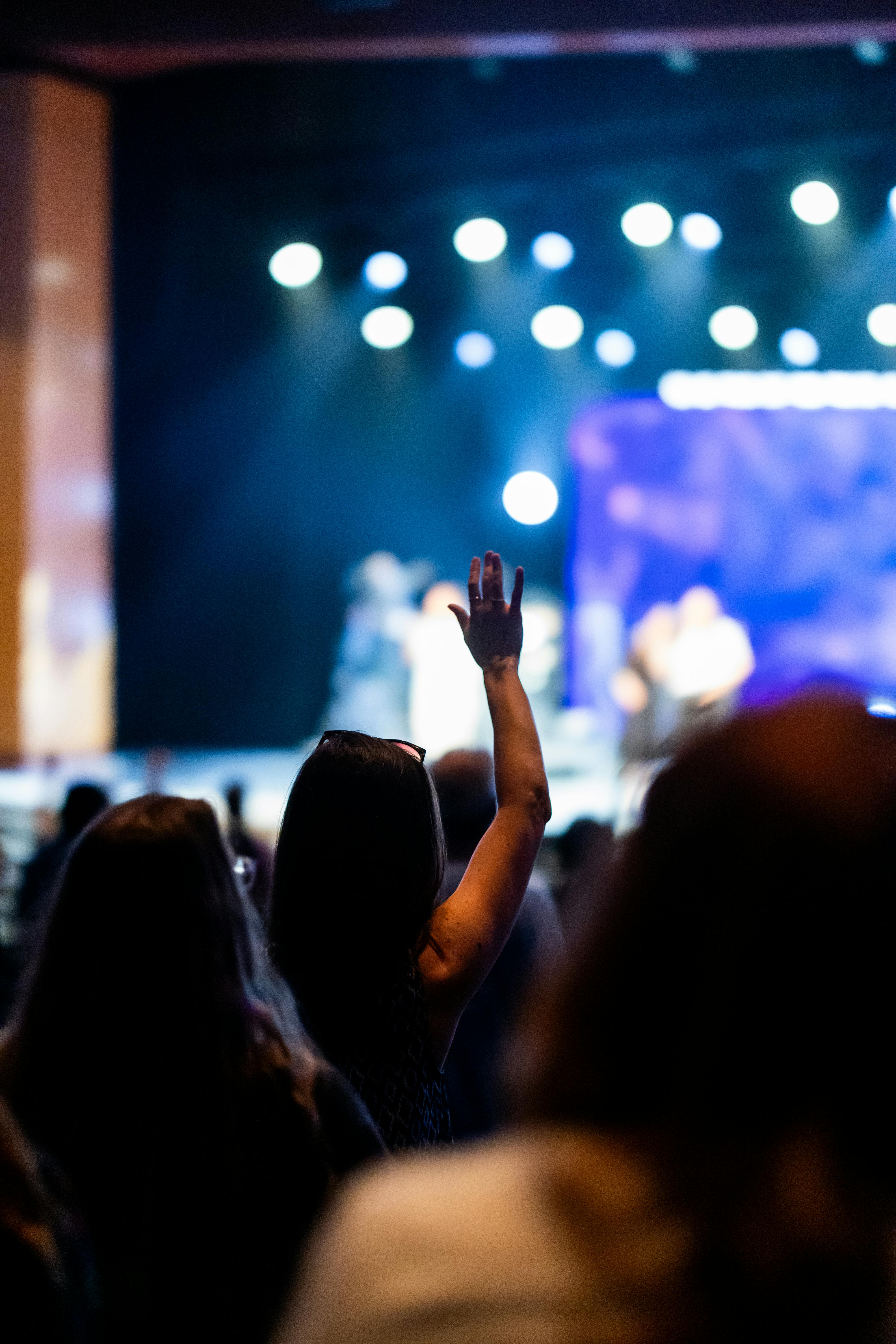 Free Excited audience raising hands at a dynamic live music concert. Stock Photo