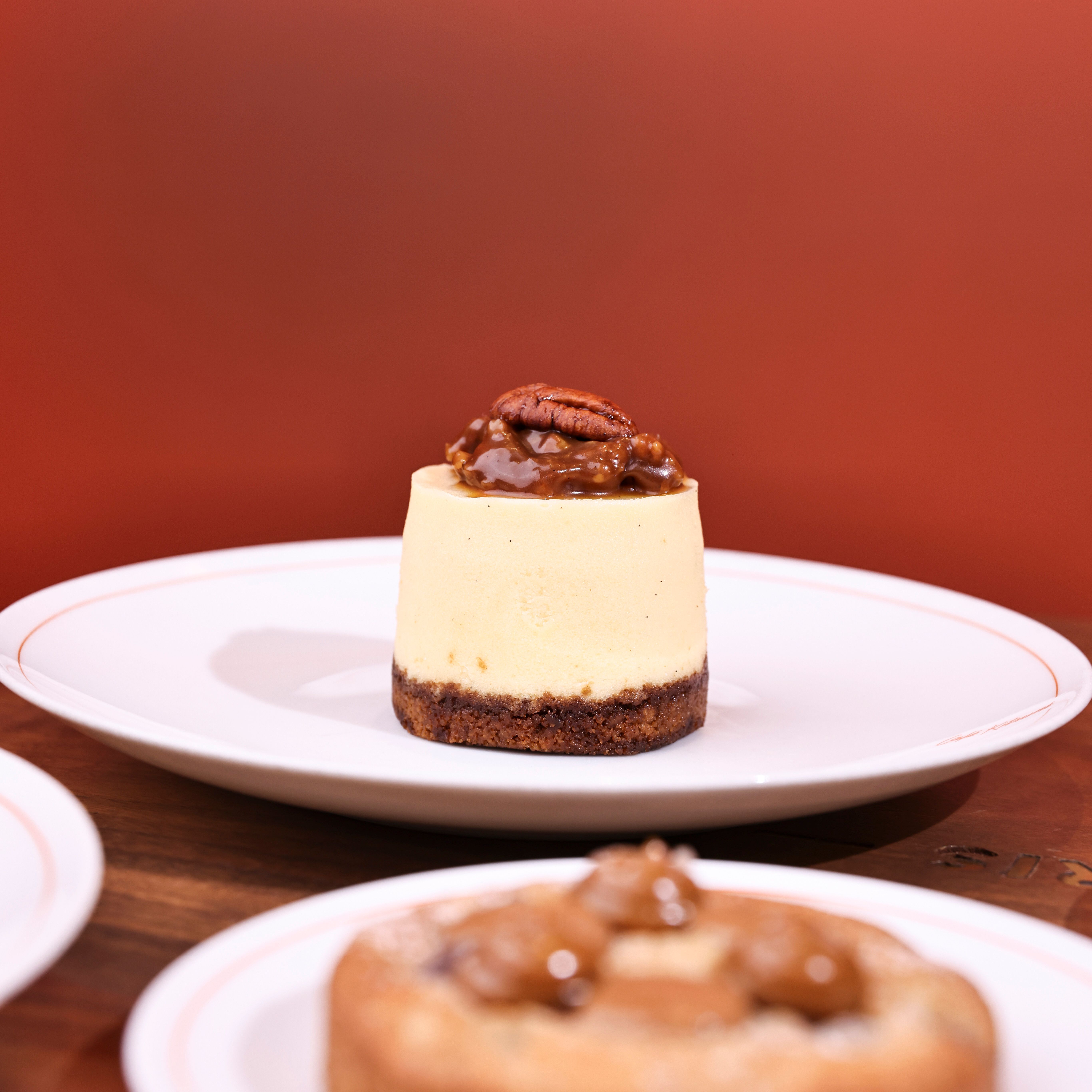 Elegant cheesecake topped with pecans and caramel on a white plate.