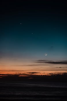 日落时分，充满活力的海平线上，新月与星星宁静地悬挂着