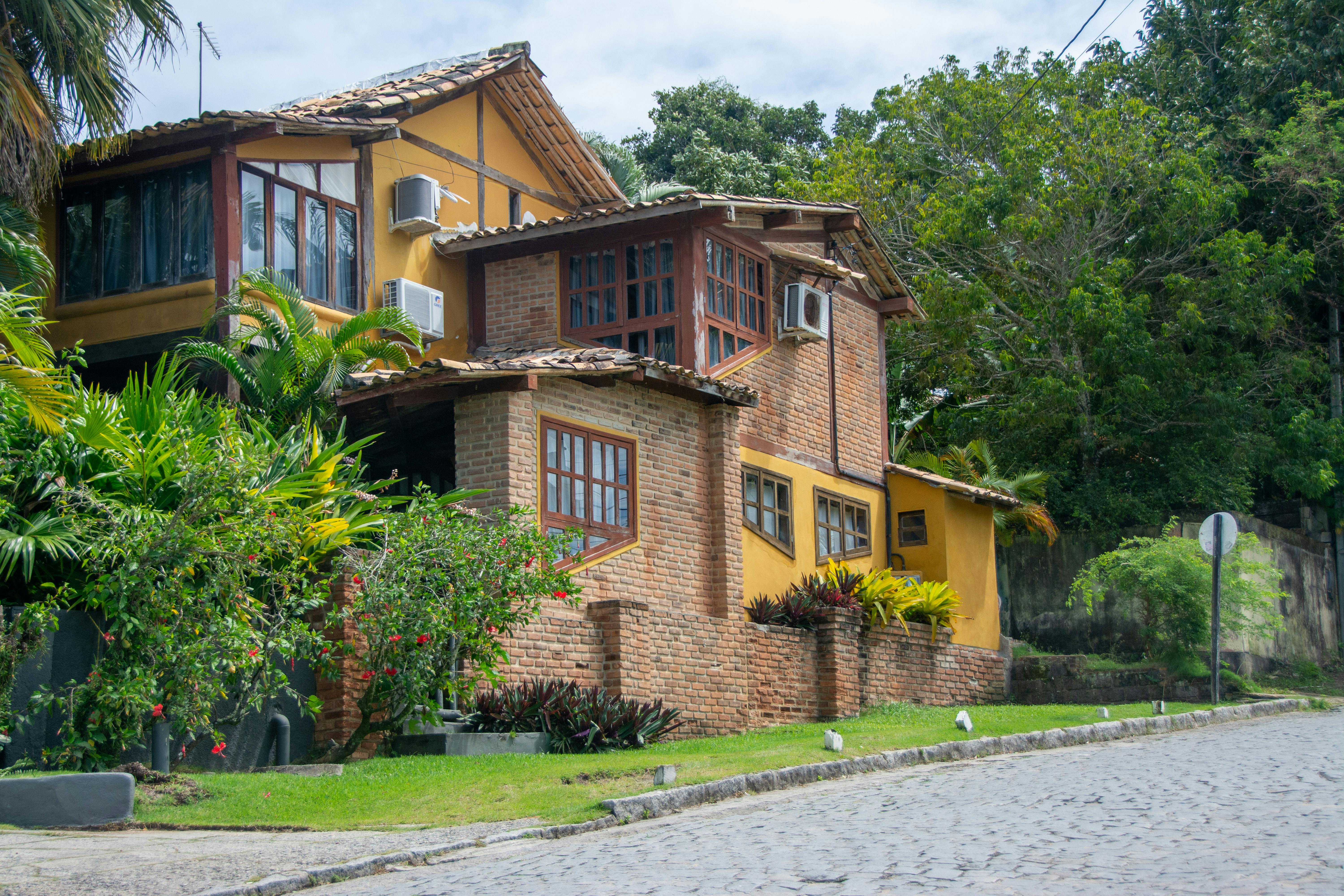 ฟรี บ้านอิฐสวยงามล้อมรอบด้วยสวนเขตร้อนในวันที่อากาศแจ่มใส คลังภาพถ่าย