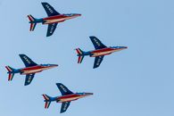 French Patrouille de France jets performing a formation flight with vibrant tricolors in Bucharest's blue skies.