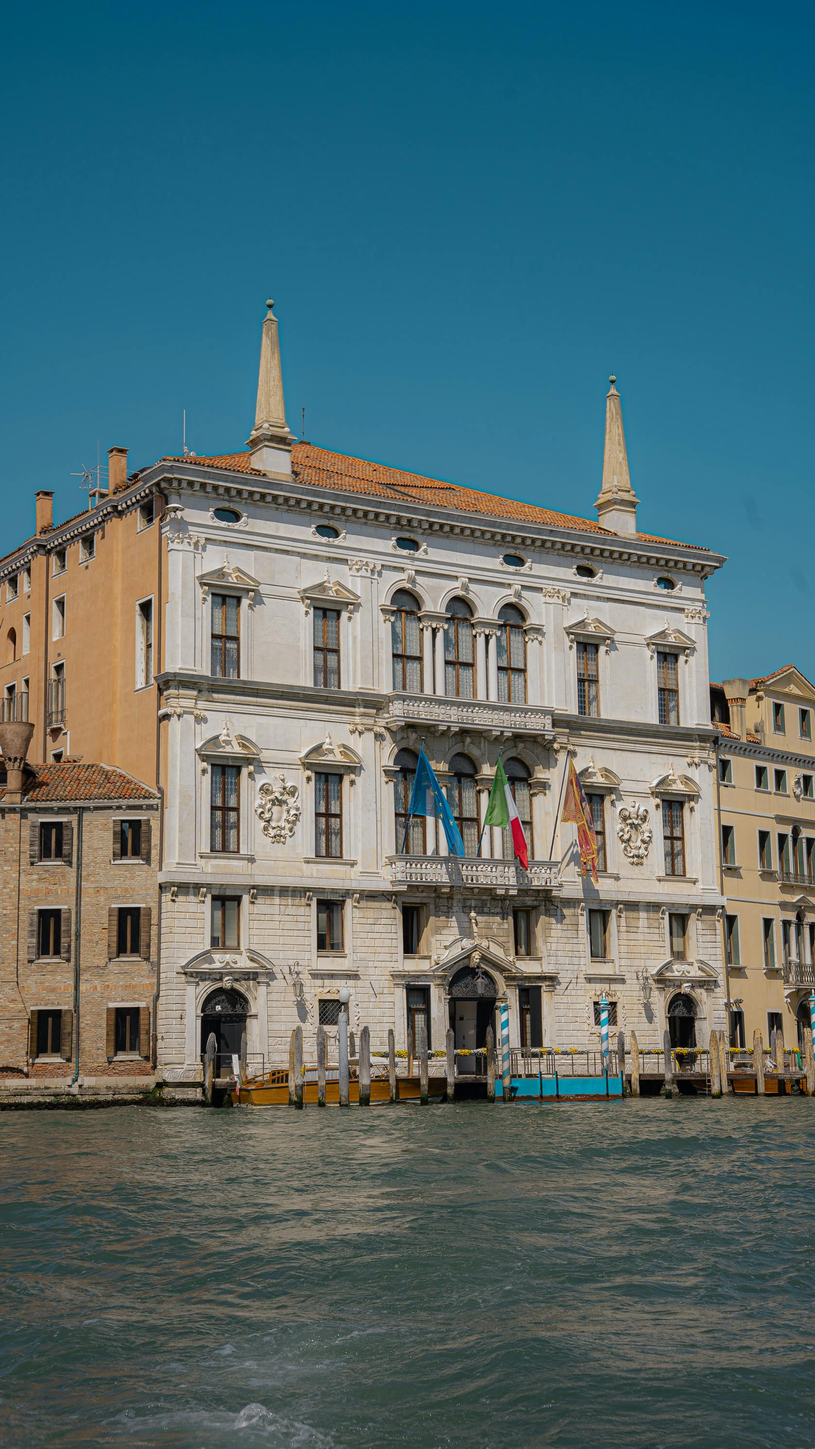 Elegant historic building in Venice, Italy, along the Grand Canal with flags displayed.