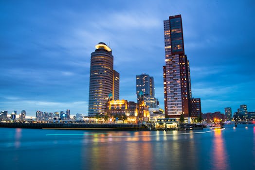 Stunning night view of Rotterdam's modern cityscape with illuminated skyscrapers reflecting in the river.