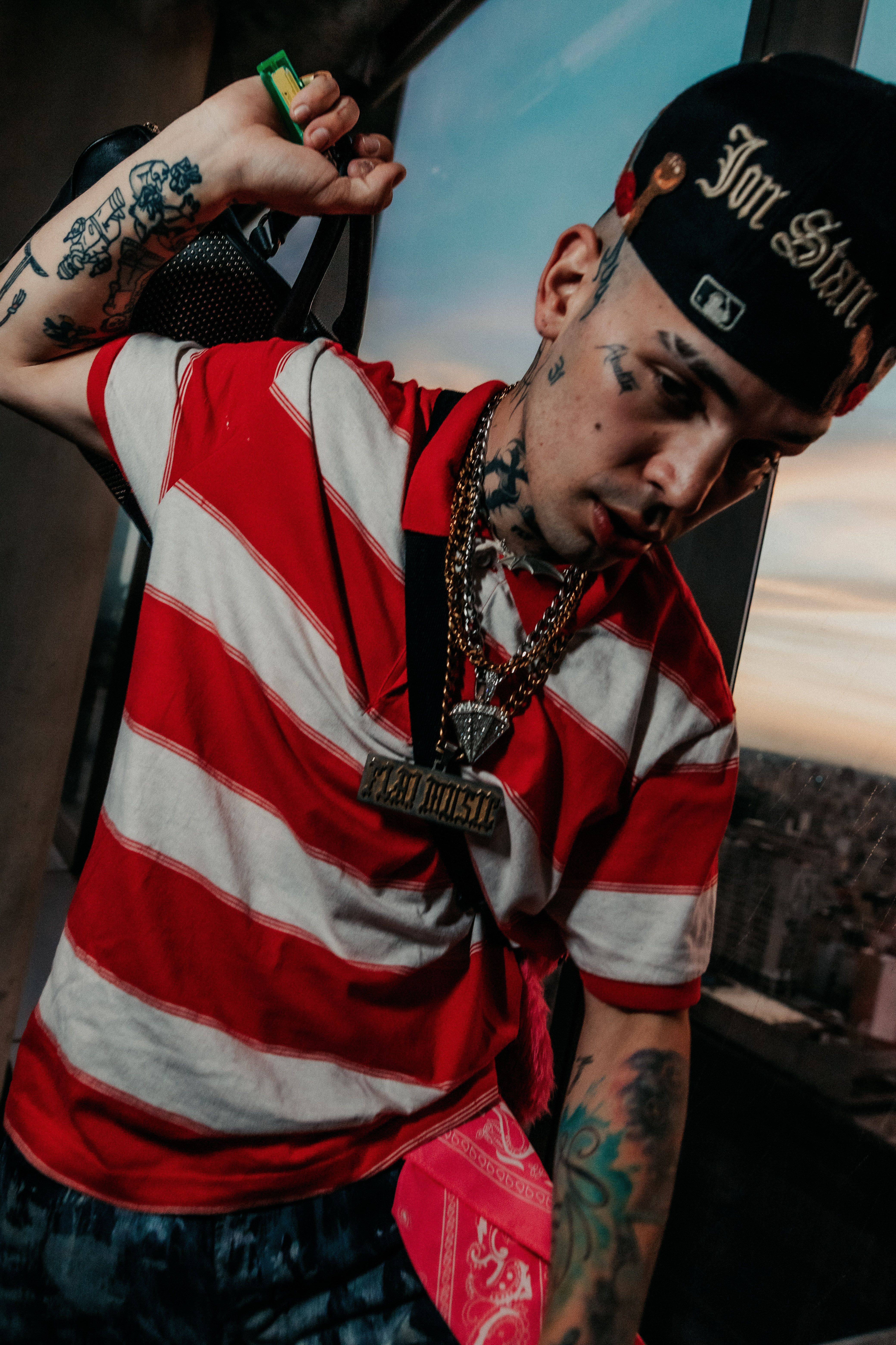 Dynamic portrait of a tattooed man in urban attire with sunset skyline in Buenos Aires.