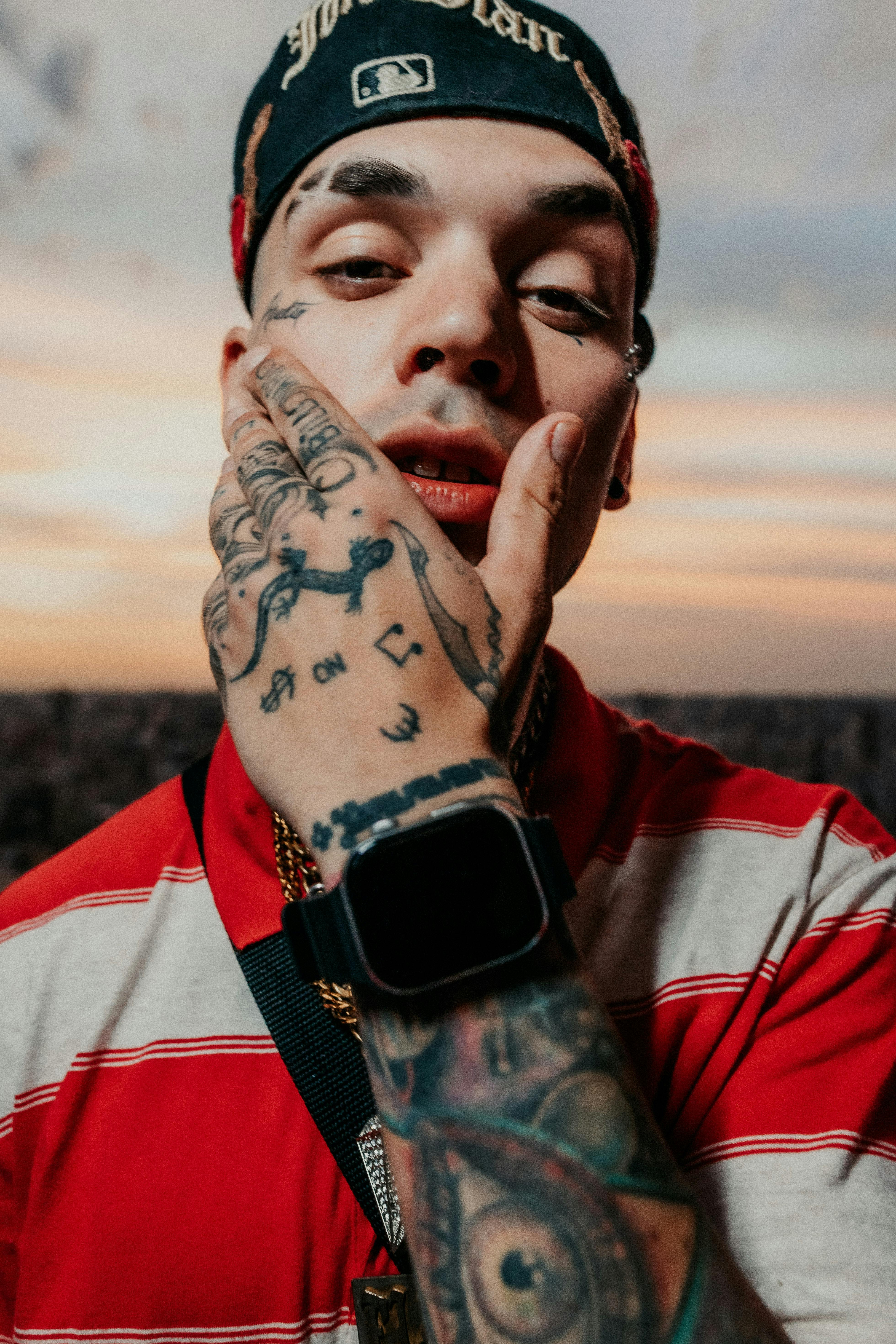 Ücretsiz Buenos Aires'te gün batımında şapka takan dövmeli genç bir adamın portresi. Stok Fotoğraflar