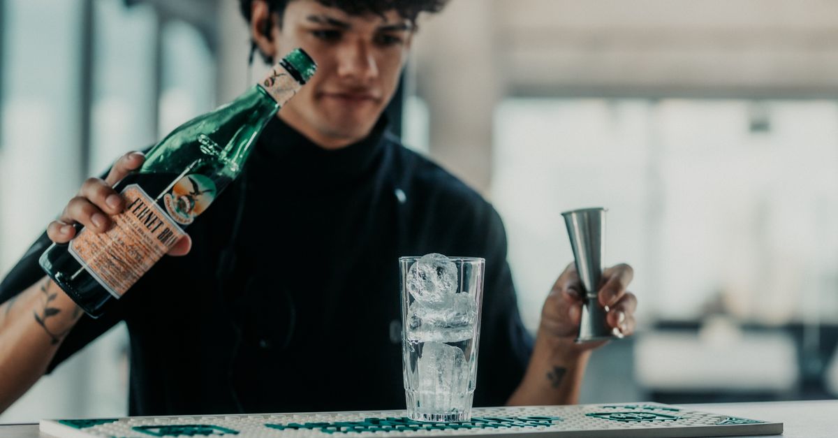 Bartender pouring Fernet into a glass with ice at a lively bar.