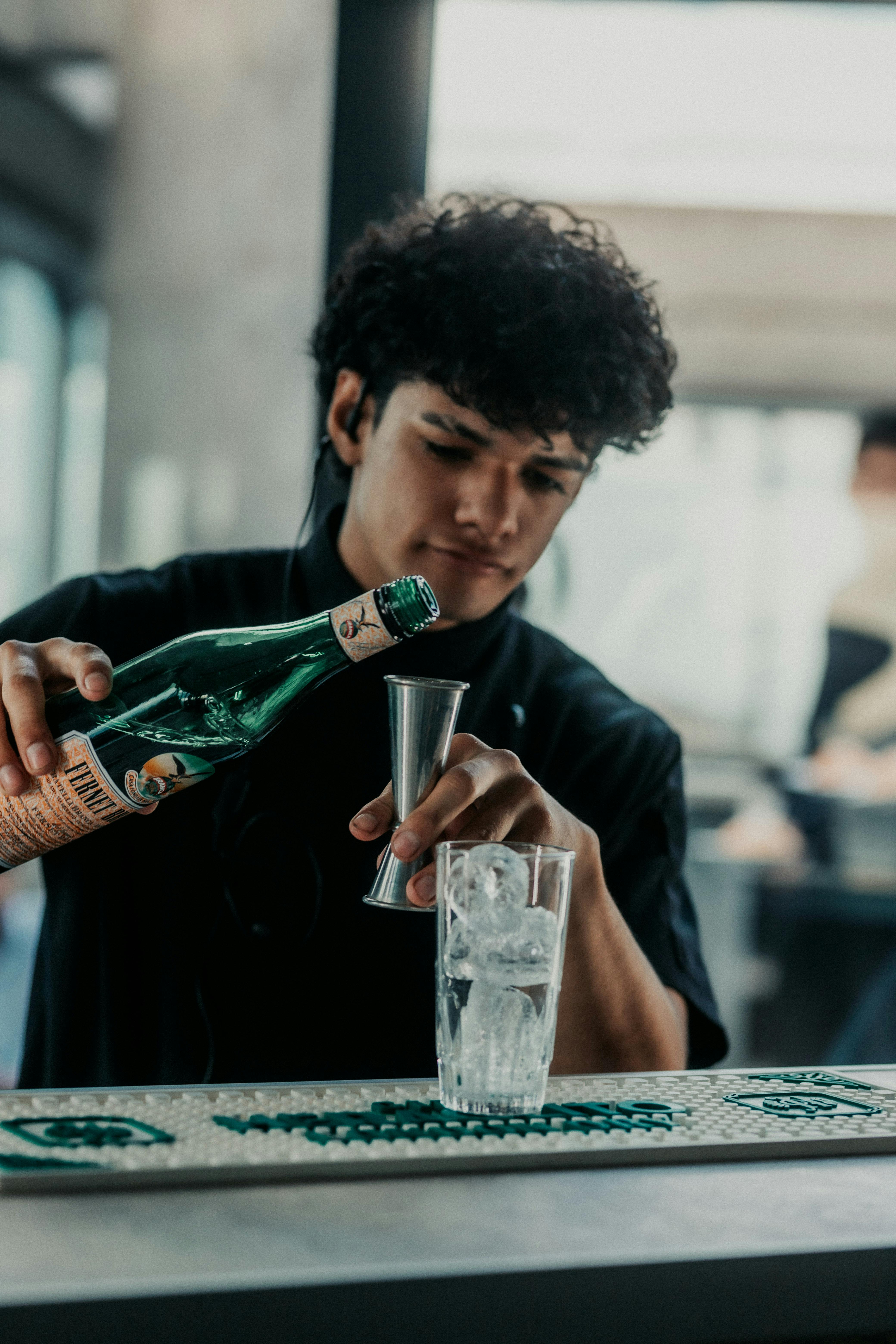 Bartender skillfully pouring fernet into a glass in a Buenos Aires bar setting, filled with cool ambiance.