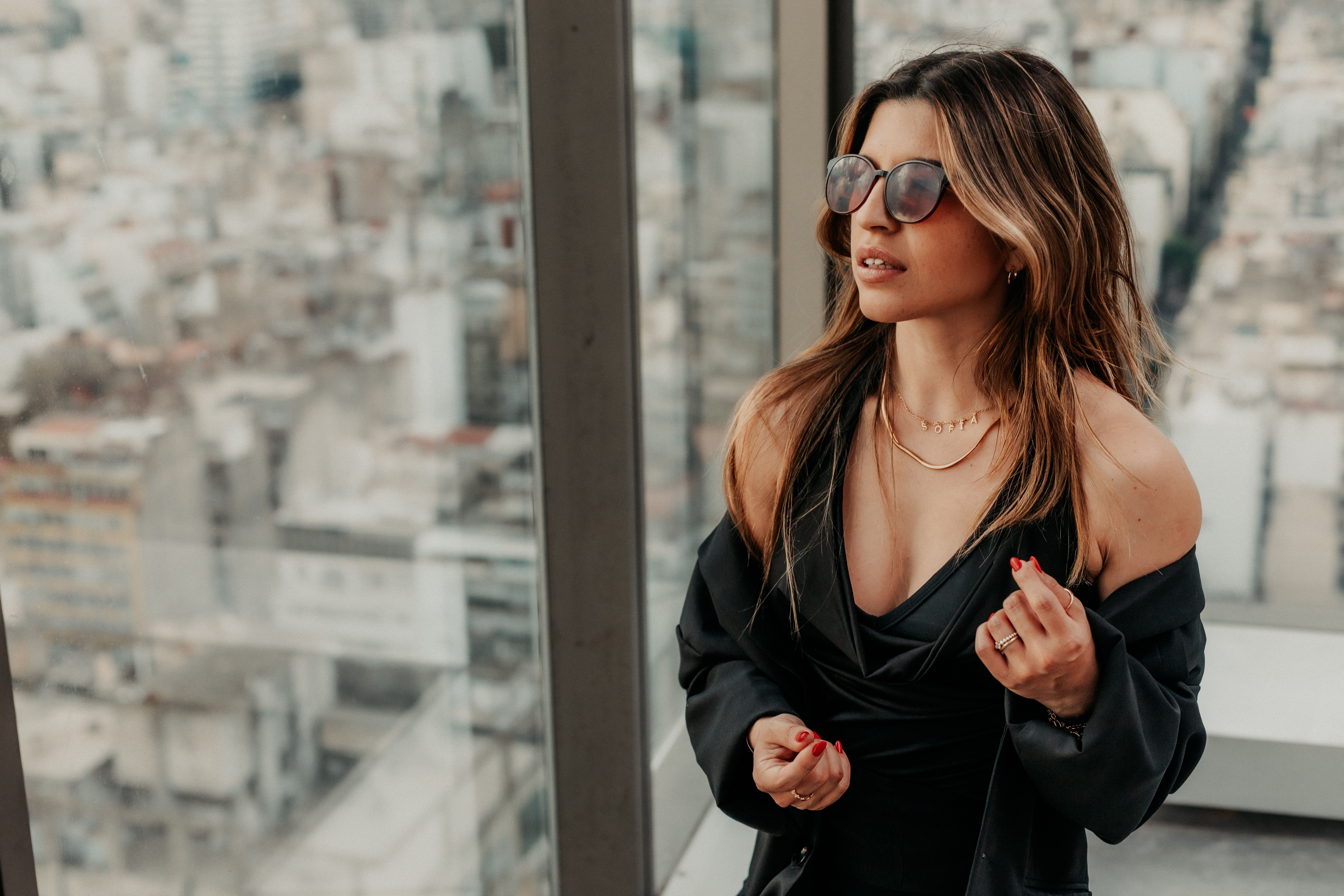 Elegant woman with sunglasses admiring Buenos Aires skyline from a high-rise building.