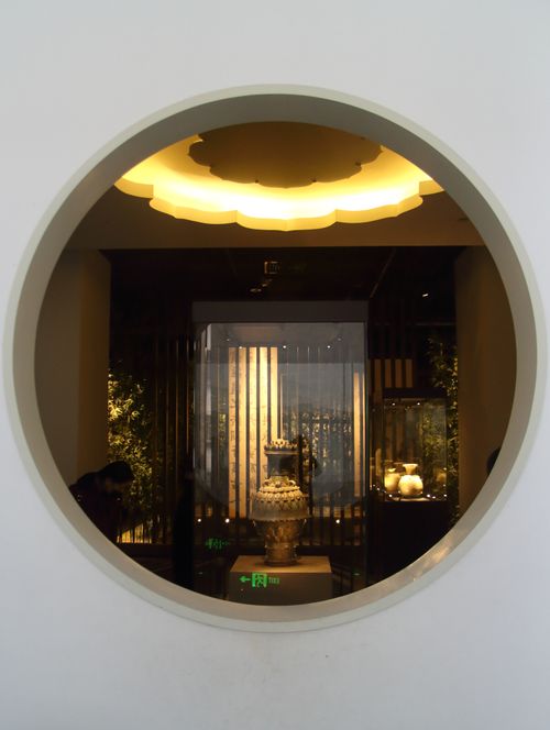 Free Circular window view of an elegantly lit interior with decorative vases. Stock Photo