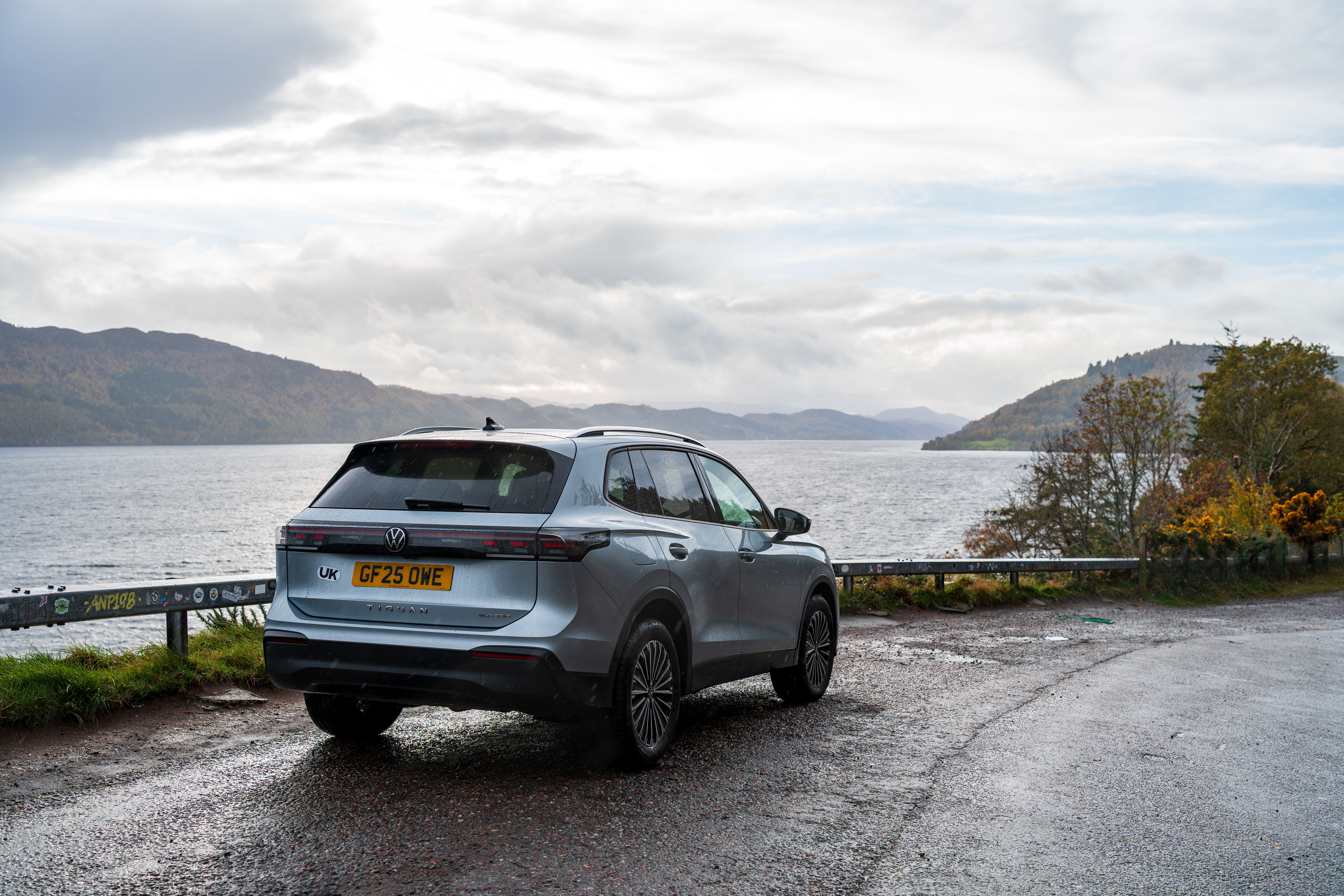 A Volkswagen SUV parked near a scenic lake with a mountainous backdrop.