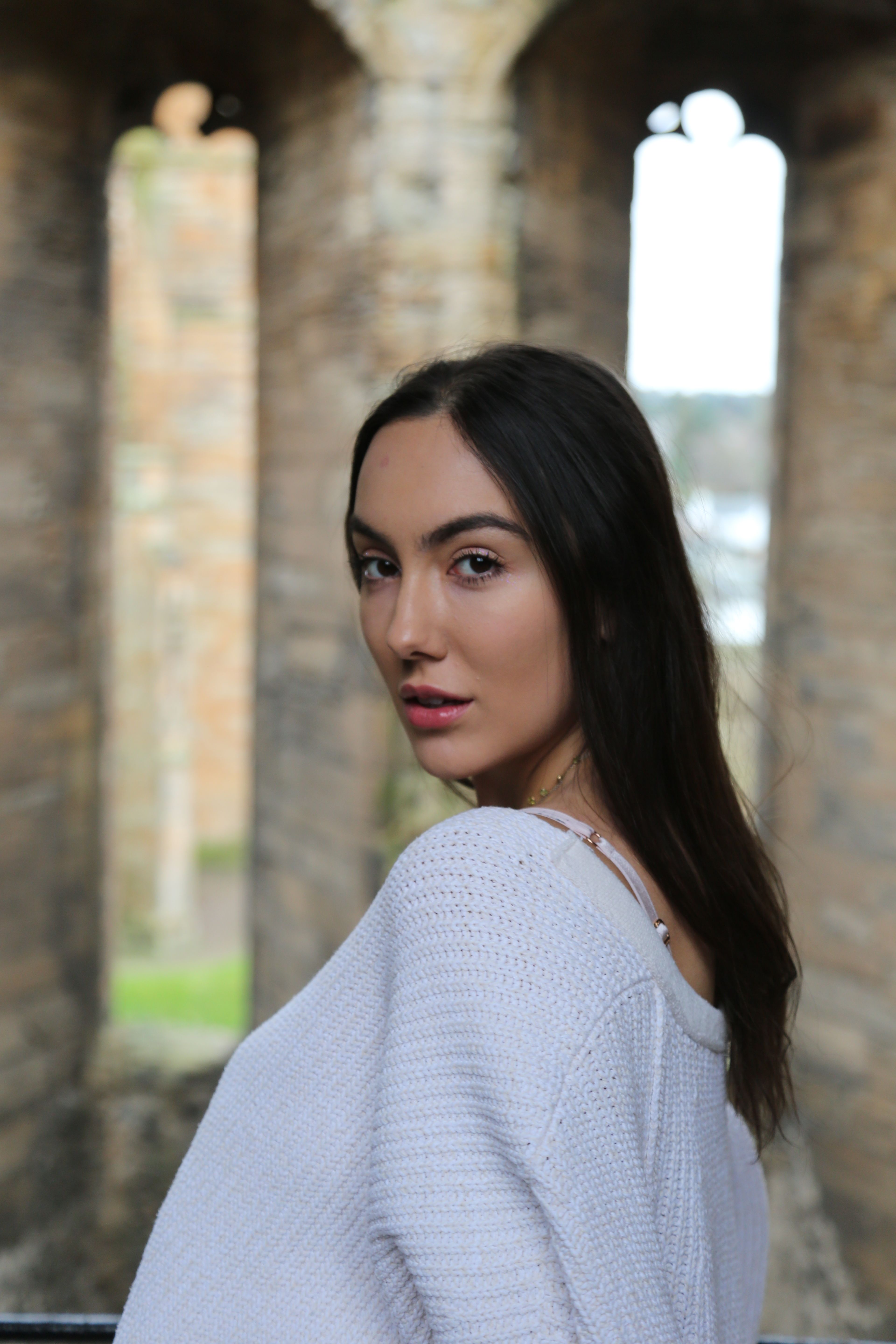 A woman poses inside ancient Scottish ruins, showcasing beauty and history.