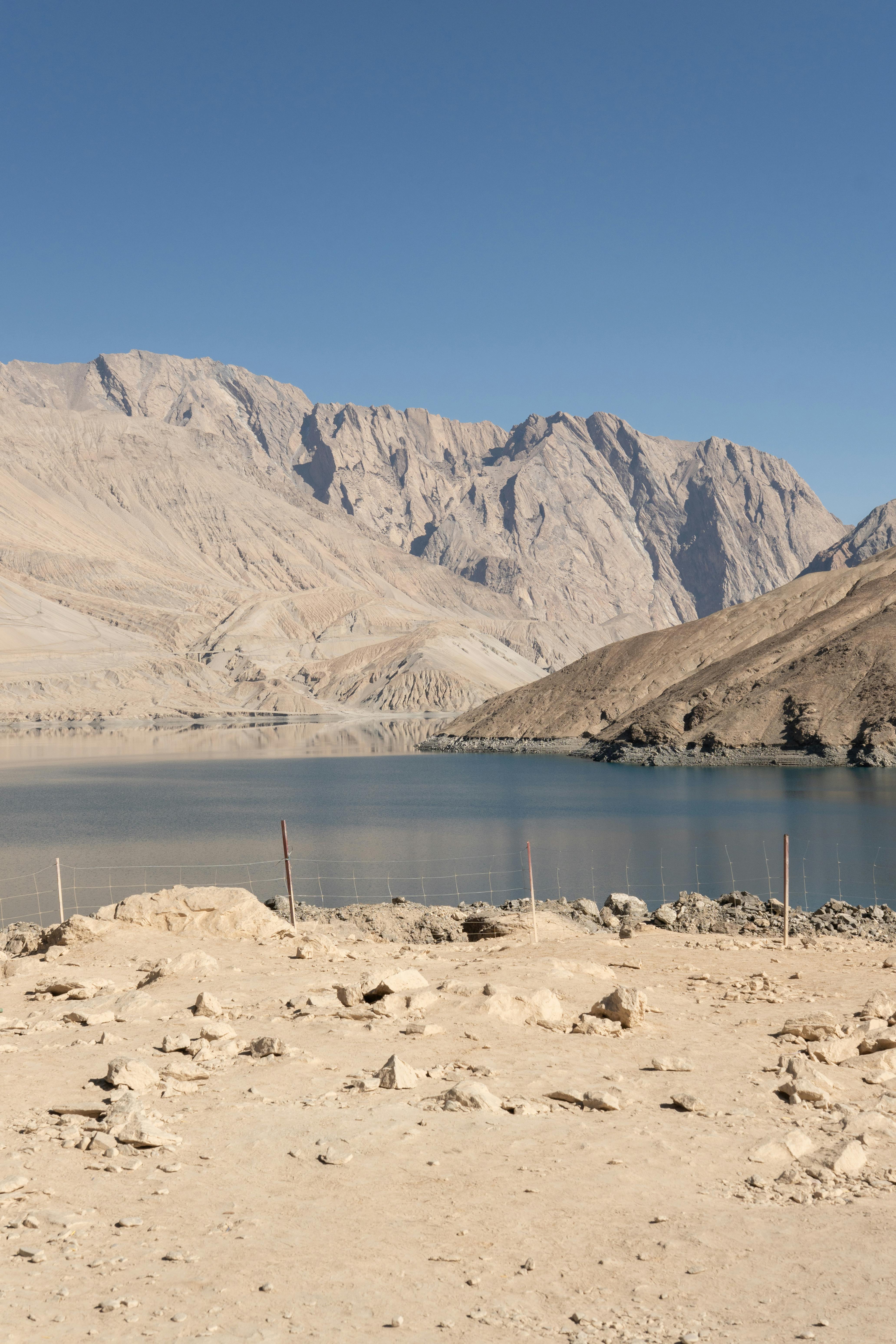 A breathtaking lake nestled between arid mountains under a clear blue sky.