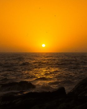 Stunning golden sunset over the ocean, casting warm hues on California's coastline with serene waves.