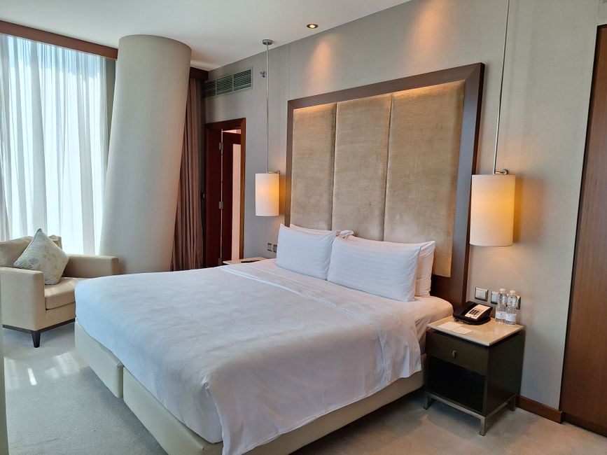 Elegant hotel bedroom with modern decor, twin lamps, and large window in Doha, Qatar.