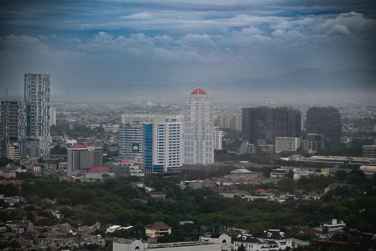 Stunning aerial view of Jakarta's skyline with modern skyscrapers and cloudy sky.