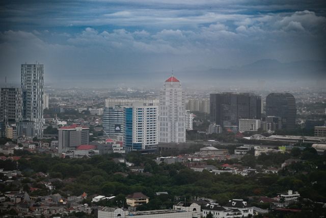 Stunning aerial view of Jakarta's skyline with modern skyscrapers and cloudy sky.