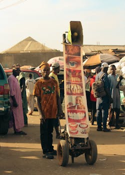 Street vendor with dental advertisement cart in a bustling African market.