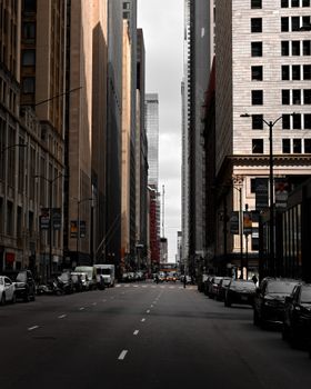 A dramatic view of downtown Chicago with towering skyscrapers and shadowed streets at dusk.