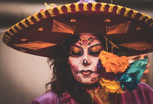 Free Close-up of a woman's face painted for Dia de los Muertos, wearing a colorful sombrero. Stock Photo