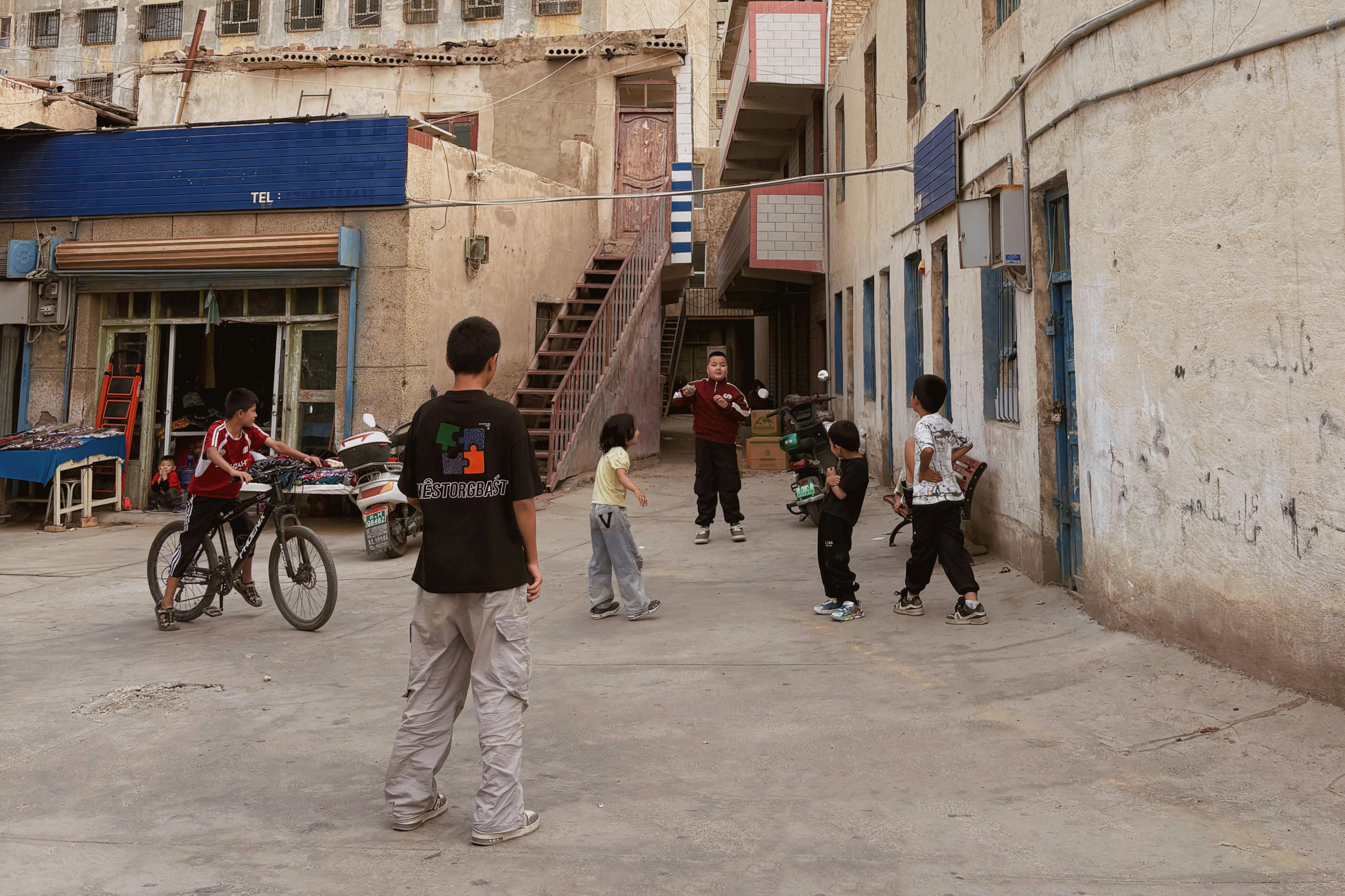 Children play in an urban alleyway with a bicycle, showcasing everyday life and culture.