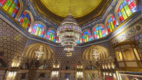 Free Intricate mosque interior with vibrant stained glass and ornate chandeliers. Stock Photo