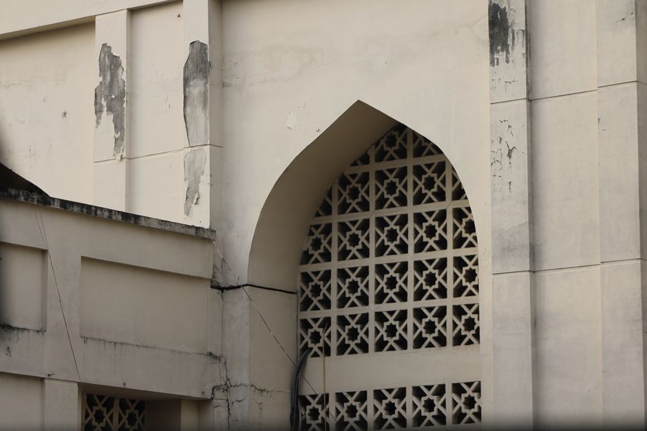 Close-up of a weathered architectural facade with geometric patterns and peeling paint.