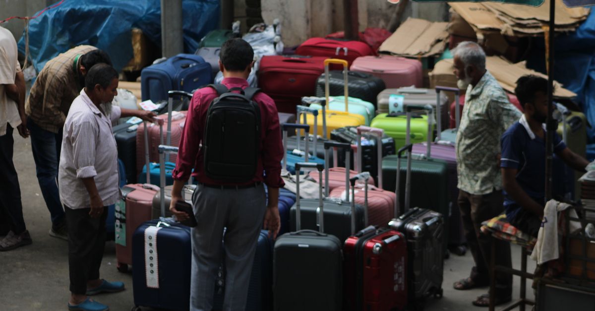 Street market scene with people browsing various colorful suitcases.