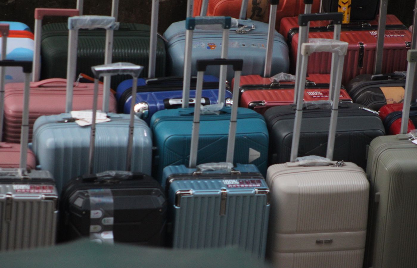 A variety of colorful suitcases with handles extended, ready for travel.