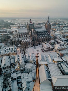 Aerial view of a snow-covered historic European city with a prominent cathedral.