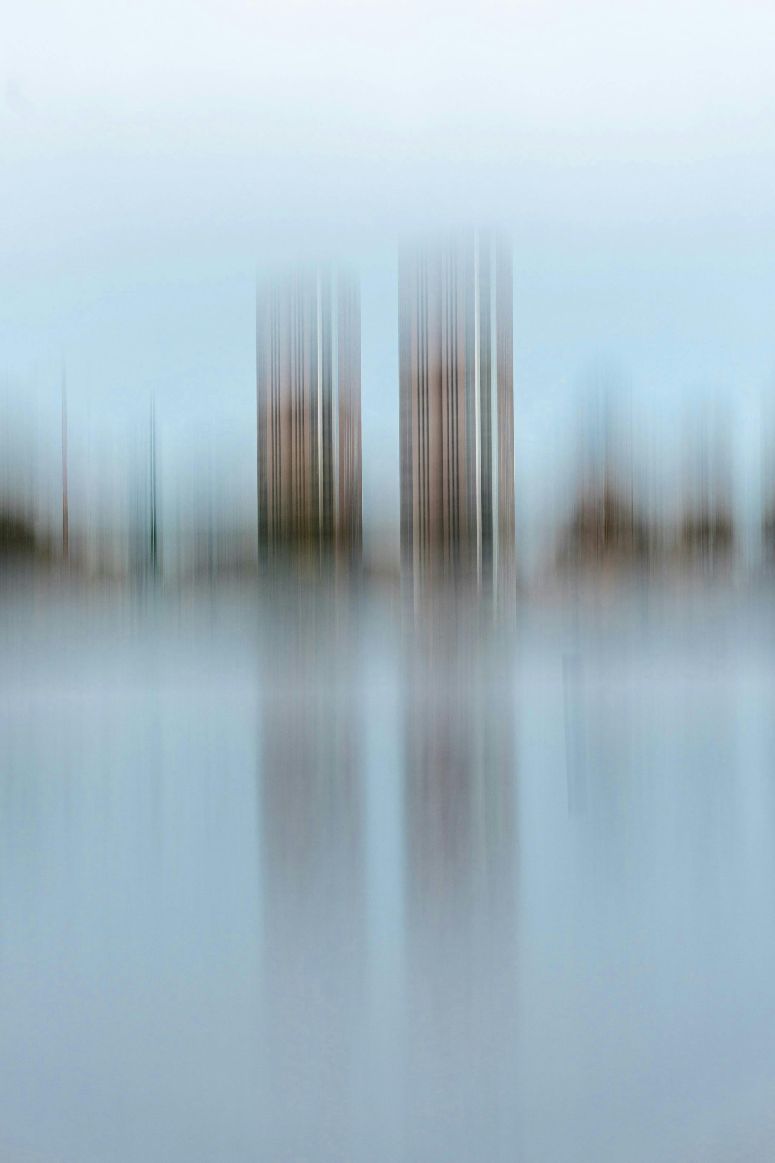 Artistic blur of skyscrapers reflecting on water, creating an abstract cityscape.